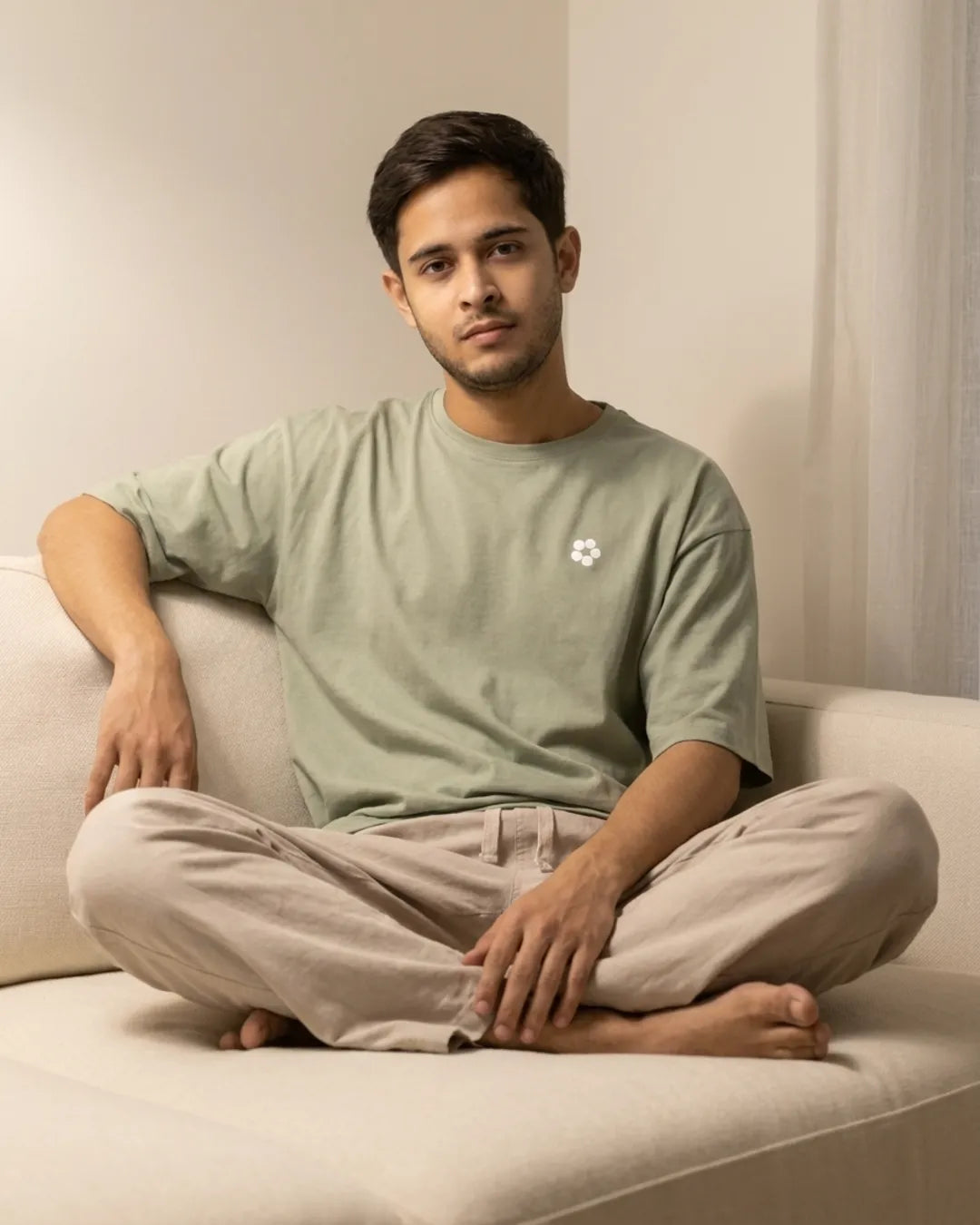 Back home, sitting cross-legged in a sage tee and linen trouser